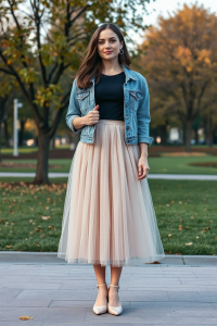 A woman in a light pastel tulle ballet skirt, paired with a black fitted blouse and a denim jacket, standing i