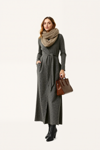 A woman wearing a long wool maxi dress with a belted waist, accessorised with a long cashmere scarf, a pair of